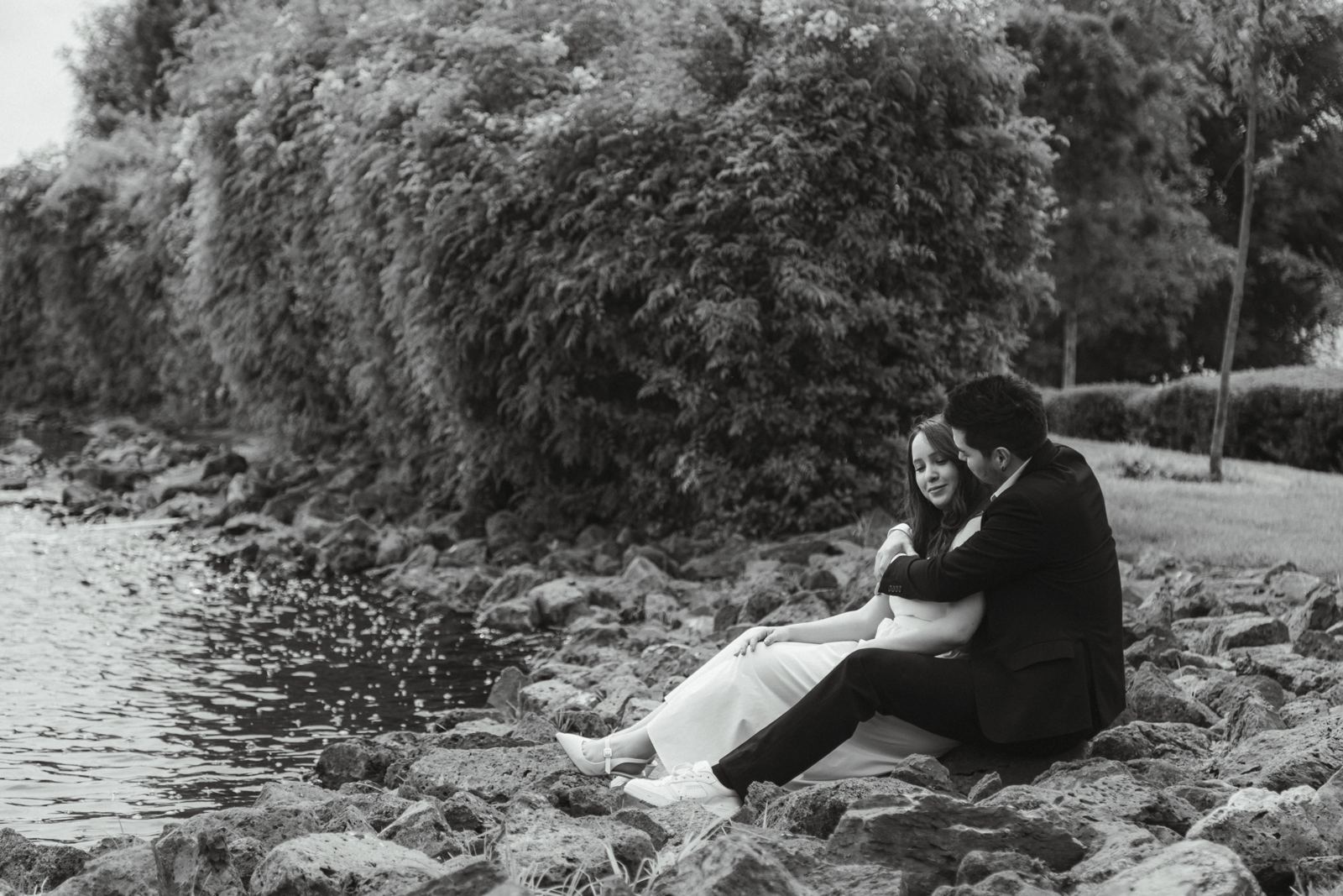 Karen e Ismael sentados a la orilla del agua, retrato en blanco y negro